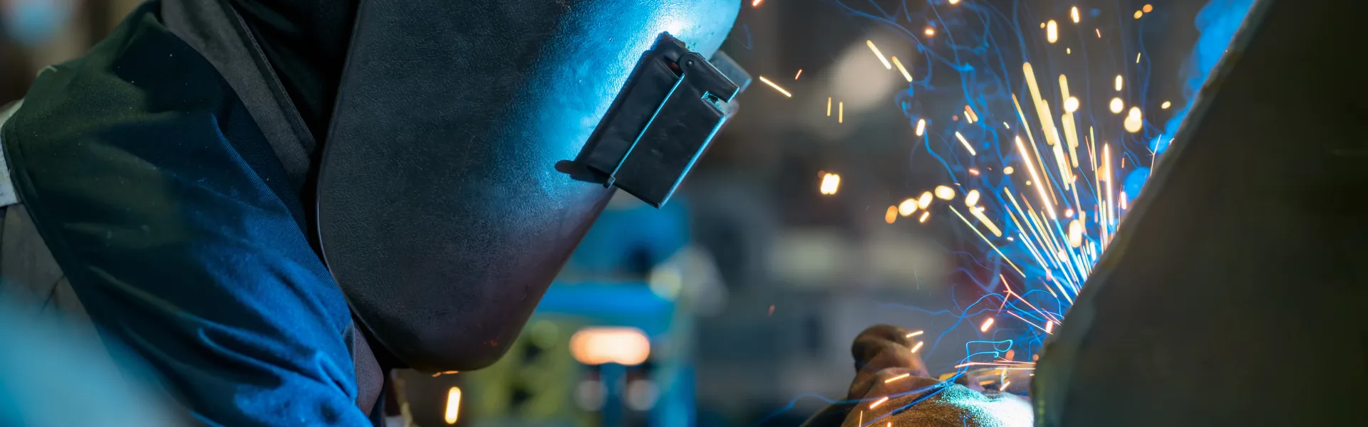 Close-up of a welder wielding sparks . Welder Welding Metal In Workshop